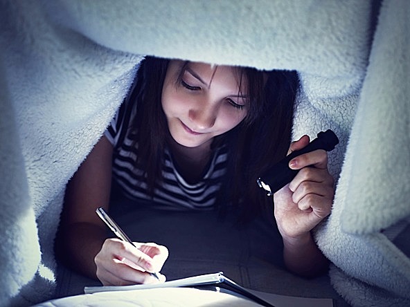 Girl writing by torchlight